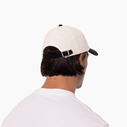 Person wearing a white cap with a black brim on a white background