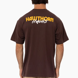 Person wearing a brown t-shirt with 'Hawthorn Hawks' text on the back, on a white background
