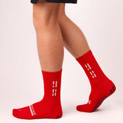 Red socks with white patterns worn by a person on a light background