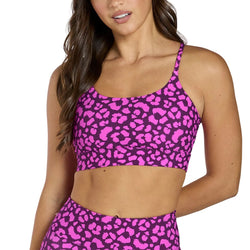 Woman wearing a pink leopard print sports bra and leggings on a gray background