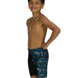 Young boy wearing black swim shorts with blue shark pattern on a white background
